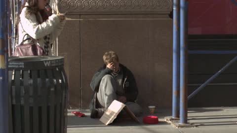 A homeless woman is resting on the street