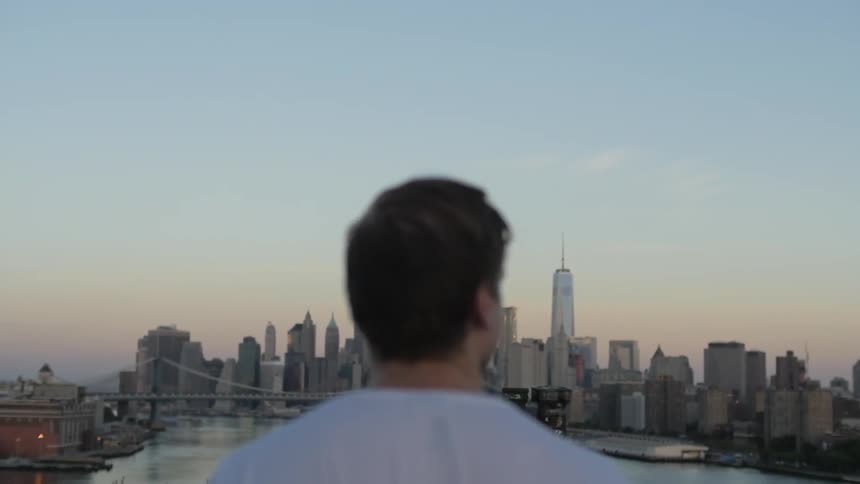A man walks toward the city at dusk