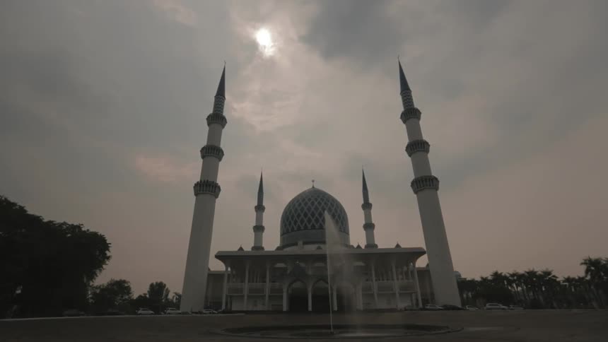 A scenery of a mosque with water fountain at cloudy days