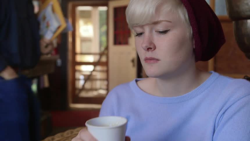 A woman drinks from a paper cup