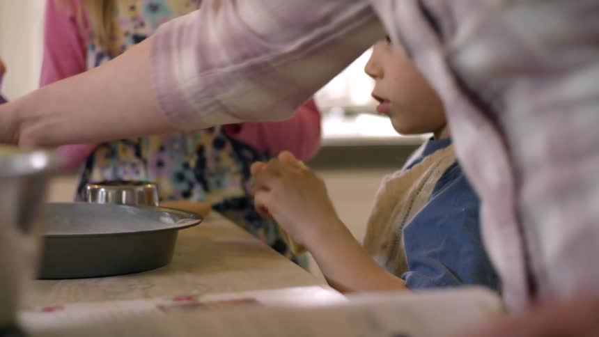 Children unwrap butter at the kitchen counter