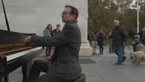 A man plays piano while people watch
