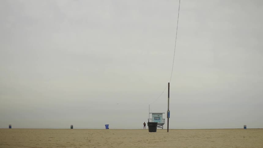 Person stands on the beach near the life guard hut