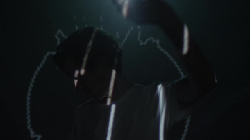 Man holds up hand to shield eyes from lights flashing on him