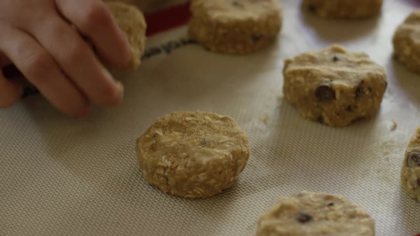 A woman puts cookie dough on a baking sheet
