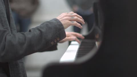 Man with tattooed fingers playing a large piano