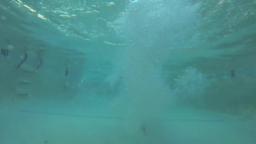 A man dives into a pool and swims underwater