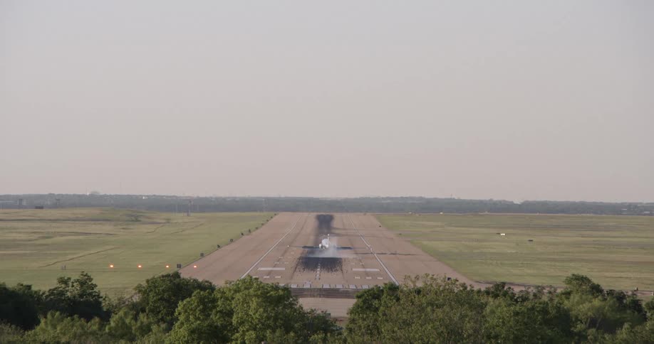 A plane on a runway with smoke around the tail area