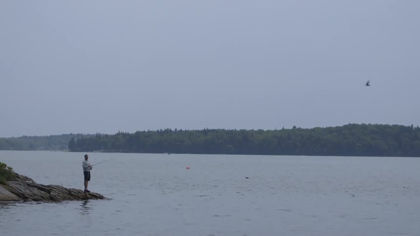 A man fishes on a river on a cloudy day