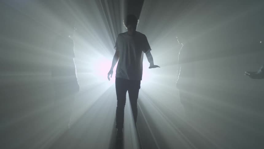 People walk in front of a bright light