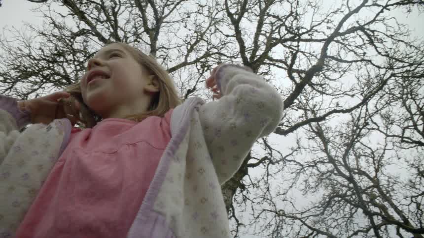 Girl laughs under the trees on a cloudy day