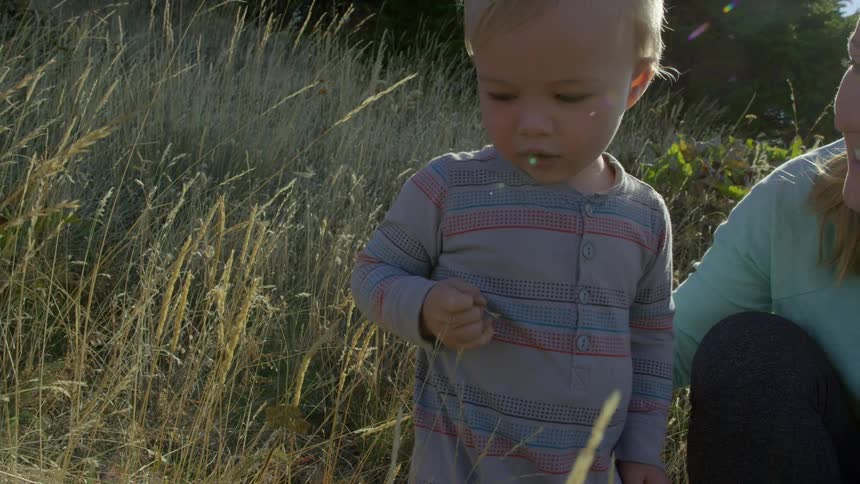 A young boy enjoying his outdoor time with his mother on a sunset evening in the woods exploring