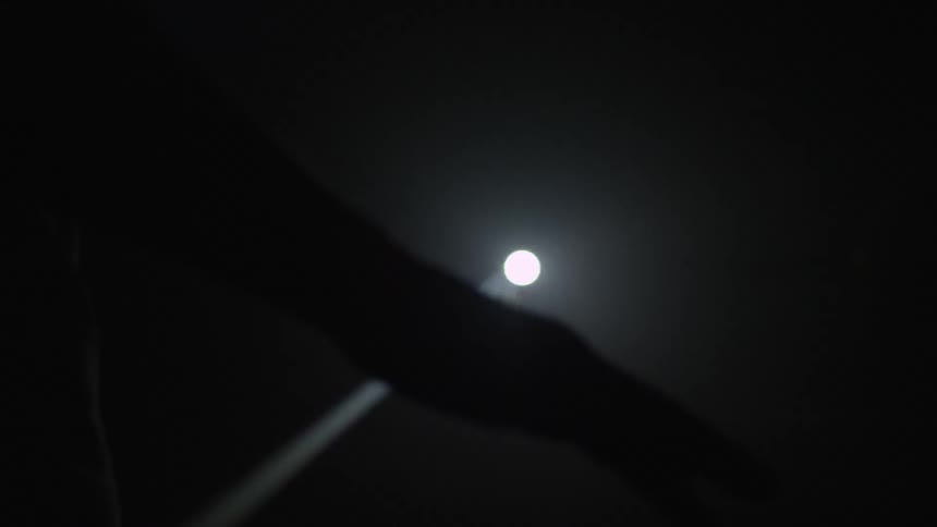 A bright light flashes behind a hand