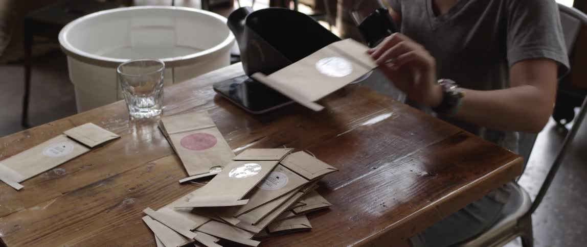 A woman stamps brown paper bags