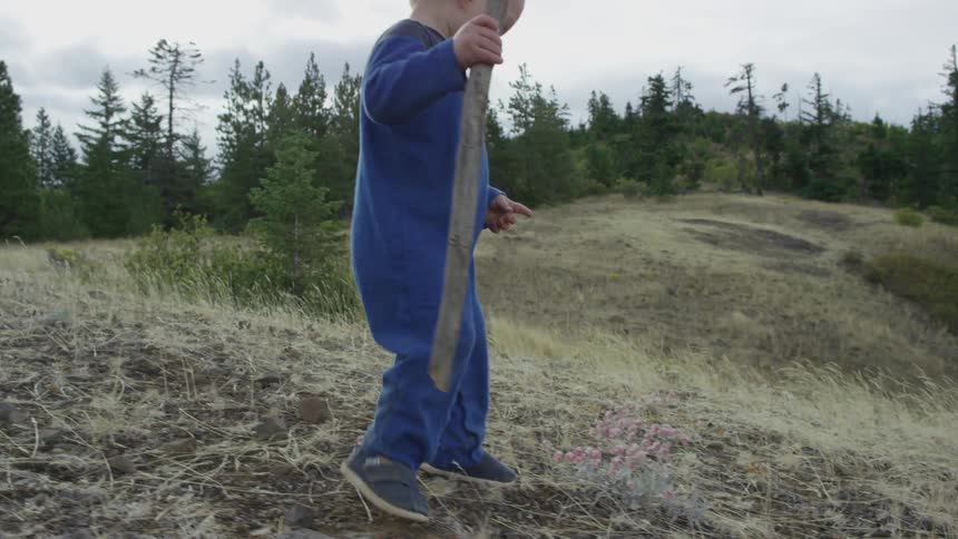 Smiling blond baby walks down a sand dune