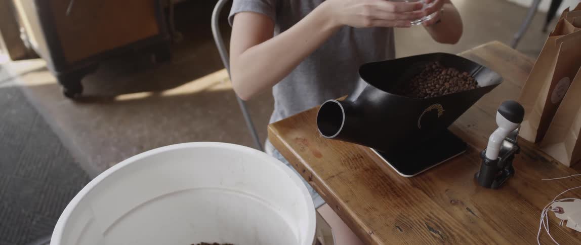 A woman scoops up coffee beans