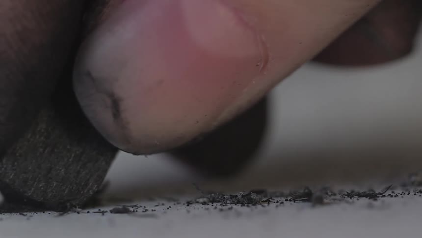 A hand writes with graphite on paper